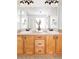 Well-lit bathroom with double sinks, oak cabinets, and a large mirror, creating a functional space at 6385 S Nelson Way, Littleton, CO 80127