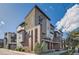 Modern three story townhome featuring mixed material exterior with brick, composite, and large windows under a bright blue sky at 3795 Depew St # D, Wheat Ridge, CO 80212