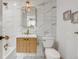 Modern bathroom with marble tile, a floating vanity, and gold fixtures at 5576 E Lehigh Ave, Denver, CO 80237