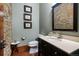 Powder room with stone accent wall, updated vanity with countertop, and hardwood floors at 2480 Castle Butte Dr, Castle Rock, CO 80109