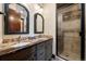 Bathroom featuring double sinks, granite countertops, framed mirrors, and a tiled walk-in shower at 2480 Castle Butte Dr, Castle Rock, CO 80109