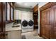 Well-appointed laundry room with stone tile, granite counters, storage, window, and large front-loading washer and dryer at 2480 Castle Butte Dr, Castle Rock, CO 80109