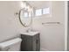 Cozy bathroom with gray vanity, a round mirror, and a white toilet at 3780 Benton St, Wheat Ridge, CO 80212