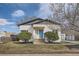Charming home featuring a modern blue door, white painted brick, and well-maintained landscaping at 3780 Benton St, Wheat Ridge, CO 80212