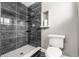 Sleek bathroom with a modern shower featuring dark marbled tile and a unique mosaic floor at 748 W 100Th Ave, Northglenn, CO 80260