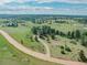 Aerial view of a house in a rural setting with green grass and mature trees at 9212 Tanglewood Rd, Franktown, CO 80116