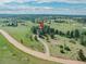 Aerial view of a house in a rural setting with green grass and mature trees at 9212 Tanglewood Rd, Franktown, CO 80116