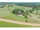 Areal view of two-story home surrounded by mature trees and green grass in rural setting at 9212 Tanglewood Rd, Franktown, CO 80116