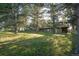 Backyard view showcasing the grassy yard, mature trees, fencing, and home exterior with a deck at 9212 Tanglewood Rd, Franktown, CO 80116