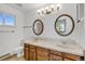 Bathroom featuring double sinks, wood cabinets, tile floor and round mirrors at 9212 Tanglewood Rd, Franktown, CO 80116