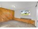 Cozy bedroom featuring wood-paneled walls, a window, and neutral carpet at 9212 Tanglewood Rd, Franktown, CO 80116