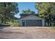 Exterior shot of the two-car garage with a driveway, side door and mature trees at 9212 Tanglewood Rd, Franktown, CO 80116