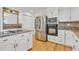 Modern kitchen featuring white cabinets, stainless steel appliances, a stylish backsplash, and beautiful hardwood flooring at 9212 Tanglewood Rd, Franktown, CO 80116