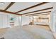 Open-concept living room with beams, carpet, and stairway to kitchen featuring wood railing at 9212 Tanglewood Rd, Franktown, CO 80116