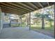 A covered patio with a concrete floor and wooden deck, overlooking a lawn with mature trees at 9212 Tanglewood Rd, Franktown, CO 80116