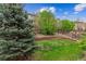 Backyard featuring a lush lawn, mature trees, terraced landscaping, and a wood fence at 22310 E Chenango Dr, Aurora, CO 80015