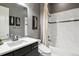 Stylish bathroom featuring a modern vanity, decorative wallpaper, and shower-tub combo at 22310 E Chenango Dr, Aurora, CO 80015
