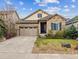 Charming home featuring a stone facade, well-manicured lawn, and attached two-car garage at 22310 E Chenango Dr, Aurora, CO 80015