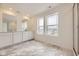 Bright bathroom with marble-style floors, double vanity sink, and glass-enclosed shower with views from two large windows at 7308 Waterleaf Trl, Littleton, CO 80125