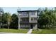 Contemporary three-story home with gray siding, black trim, balcony, and manicured lawn at 7308 Waterleaf Trl, Littleton, CO 80125