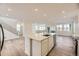 Open kitchen with white cabinets, stainless steel appliances, and a large center island flowing into the living area at 7308 Waterleaf Trl, Littleton, CO 80125