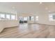 Bright, open living room with wood-look flooring, large windows, and sliding glass door to the outside at 7308 Waterleaf Trl, Littleton, CO 80125