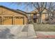 Inviting townhome featuring a two-car garage and a charming exterior with wood paneling and a stone chimney at 9088 W 88Th Cir, Westminster, CO 80021