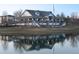 Exterior view of a clubhouse with reflection on the lake in front and green lawn around the building at 18039 E 108Th Pl, Commerce City, CO 80022