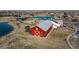 Exterior view of a red barn-style clubhouse with a view of a lake and homes in the background at 18039 E 108Th Pl, Commerce City, CO 80022