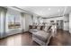 Spacious living room featuring hardwood floors, modern gray sofa, and an open layout connecting to the kitchen at 18039 E 108Th Pl, Commerce City, CO 80022