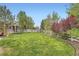 Green backyard with a white picket fence, large trees, a trampoline, and storage shed at 23882 E Alabama Dr, Aurora, CO 80018