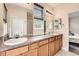 Bright bathroom featuring double sinks, a large mirror, wood cabinetry, and plenty of counter space at 23882 E Alabama Dr, Aurora, CO 80018