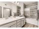 Bright bathroom featuring double vanity, updated fixtures, gray cabinets, and tiled shower at 18657 Stroh Rd # 4103, Parker, CO 80134