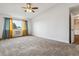 Bright bedroom with neutral carpet, ceiling fan, and double paned windows with colorful drapes at 795 S Alton Way # 5D, Denver, CO 80247