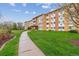 Apartment building surrounded by a green lawn with a sidewalk in the foreground at 795 S Alton Way # 5D, Denver, CO 80247