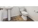 Clean bathroom with pedestal sink, toilet, and wood-look floor at 6575 N Nepal St, Aurora, CO 80019