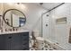 Modern bathroom boasts a navy vanity, round mirror, stylish tile floor, and glass-enclosed shower at 8890 S Quatar Ct, Aurora, CO 80016