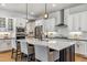 Modern kitchen features white cabinets, stainless appliances, an island with bar seating and pendant lighting at 8890 S Quatar Ct, Aurora, CO 80016