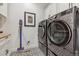 Modern laundry room with stainless steel washer/dryer and patterned floors at 8890 S Quatar Ct, Aurora, CO 80016