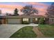 Attractive brick home with manicured lawn, an attached garage, and a patterned concrete driveway during sunset at 2243 S Olive St, Denver, CO 80224
