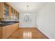 Bright kitchen featuring hardwood floors, wooden cabinets, black counters, stainless steel fixtures and shuttered windows at 2243 S Olive St, Denver, CO 80224