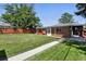 Lush backyard with a well-kept lawn, a concrete pathway, and a red fence surrounding the property at 25 S Winona Ct, Denver, CO 80219