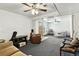 Spacious carpeted living room featuring two ceiling fans, comfortable seating, and a classic wood entry door at 25 S Winona Ct, Denver, CO 80219