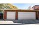 Two-car garage featuring two separate white doors and brown siding, set against a blue sky with sparse foliage at 2335 Stout St, Denver, CO 80205