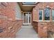 Brick front entrance with a wood door and stone steps at 1 Mountain Birch, Littleton, CO 80127