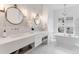 Bright bathroom featuring a double sink vanity, elegant mirrors, and a luxurious soaking tub by the window at 15116 Lyons Ridge Dr, Morrison, CO 80465