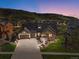 Stunning exterior of a two-story home with beautiful landscaping and a large driveway at dusk at 15116 Lyons Ridge Dr, Morrison, CO 80465