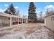 This backyard features a covered patio area with outdoor seating, a tall tree, and partial snow coverage at 3298 S Eudora St, Denver, CO 80222