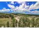 Scenic aerial view of wooded property with athletic fields and mountain views under a vibrant blue sky at 10550 Highway 73, Conifer, CO 80433