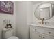 Chic half-bathroom with a vanity, gold hardware, decorative mirror, and toilet at 12580 Boggs St, Parker, CO 80134